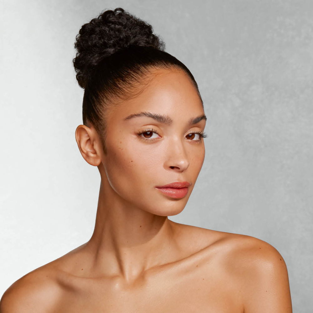 Frau mit hochgestecktem Haar und nackten Schultern blickt leicht gedreht